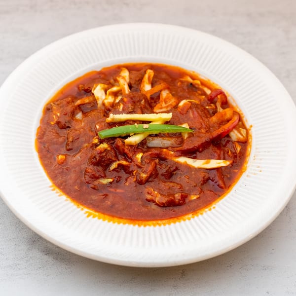 Indian Spice's chicken chili, a vibrant red curry with chicken, peppers, and green garnish.