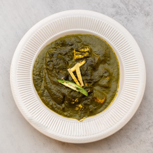 Palak Paneer, a vibrant green Indian spinach and cheese dish, garnished with ginger and chili.