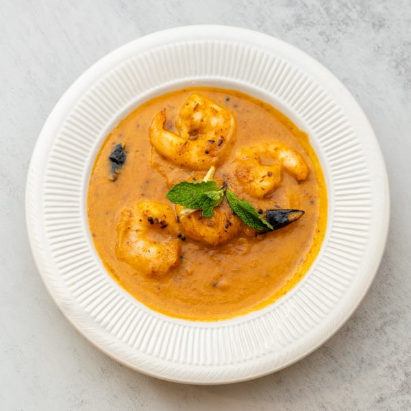 Indian Spice's shrimp curry, garnished with mint, served in a white bowl.