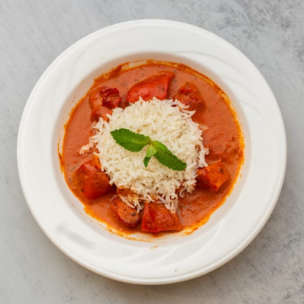 Indian Spice's chicken tikka masala with rice and a mint garnish in a white bowl.
